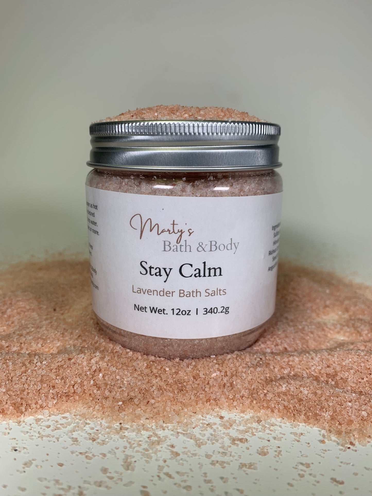 12 oz jar of Stay Calm lavender bath salt/bath salts, surrounded by natural Himalayan Pink Salt.