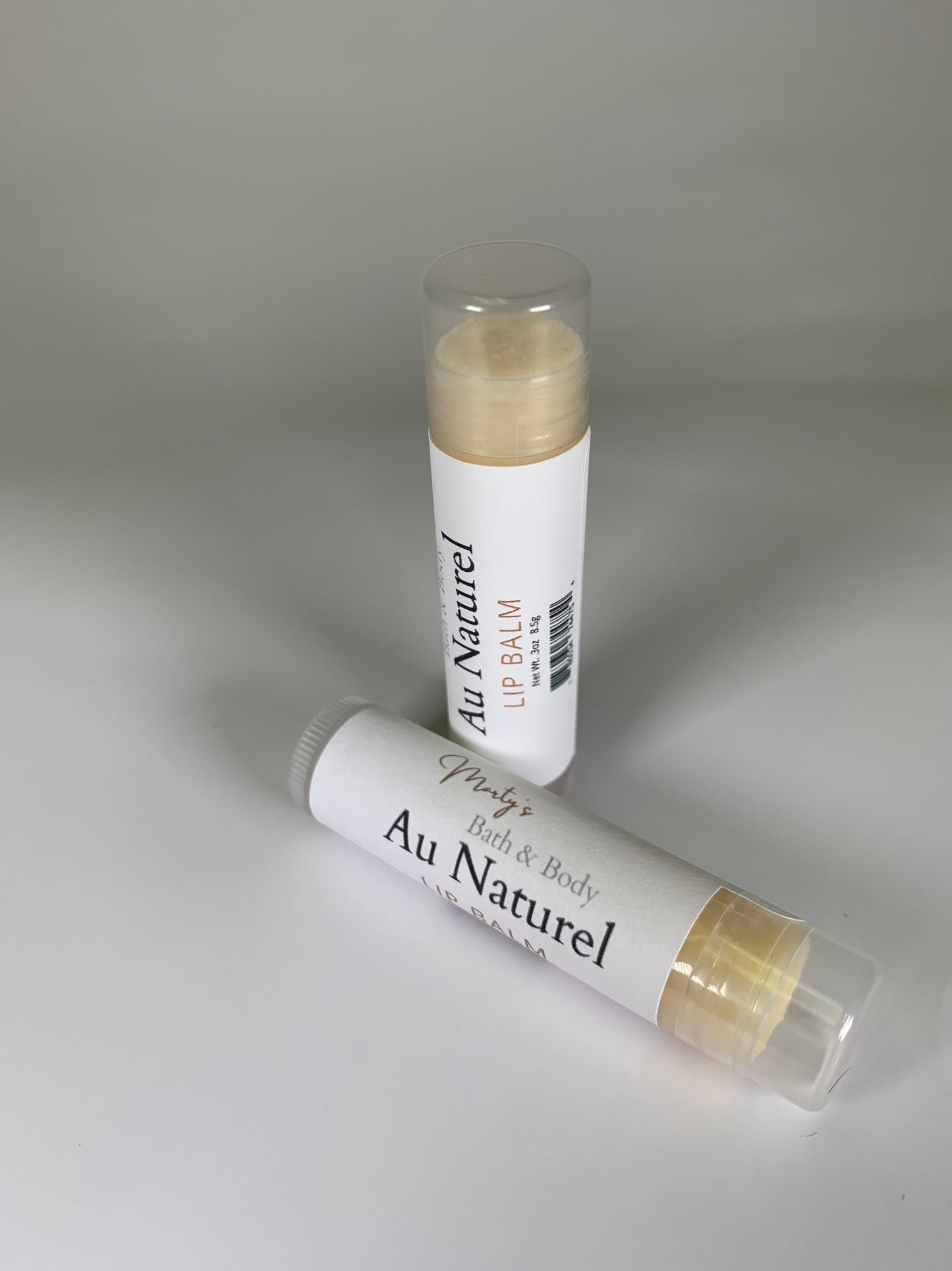 Two handmade lip balms in Au Naturel flavor. One is standing up with the other lying down.