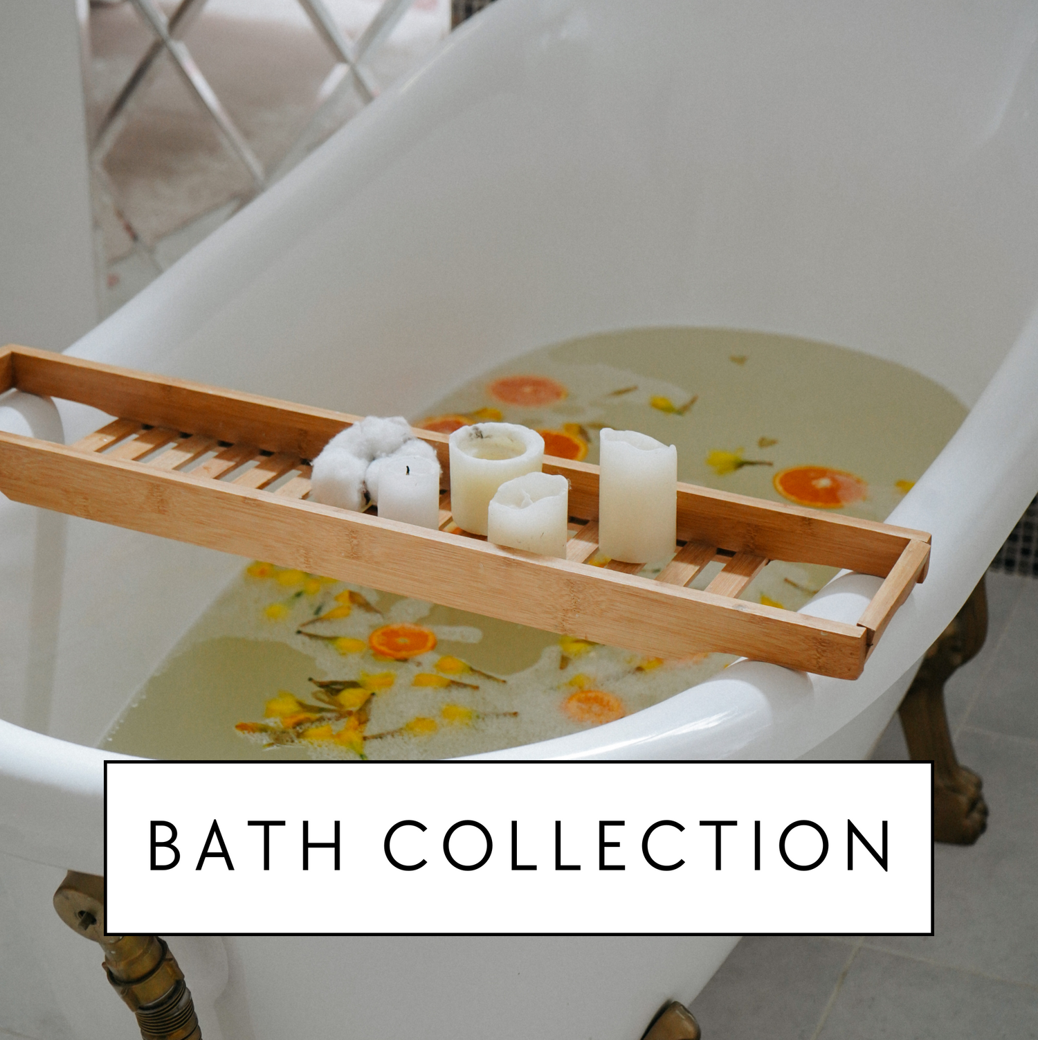 A bath tub filled with water, botanicals and orange slices. The tub is surrounded by candles to indicate an luxurious and relaxing bath. The photo has the words "bath collection" on it to show where to find the line of natural bath salts/soaks.