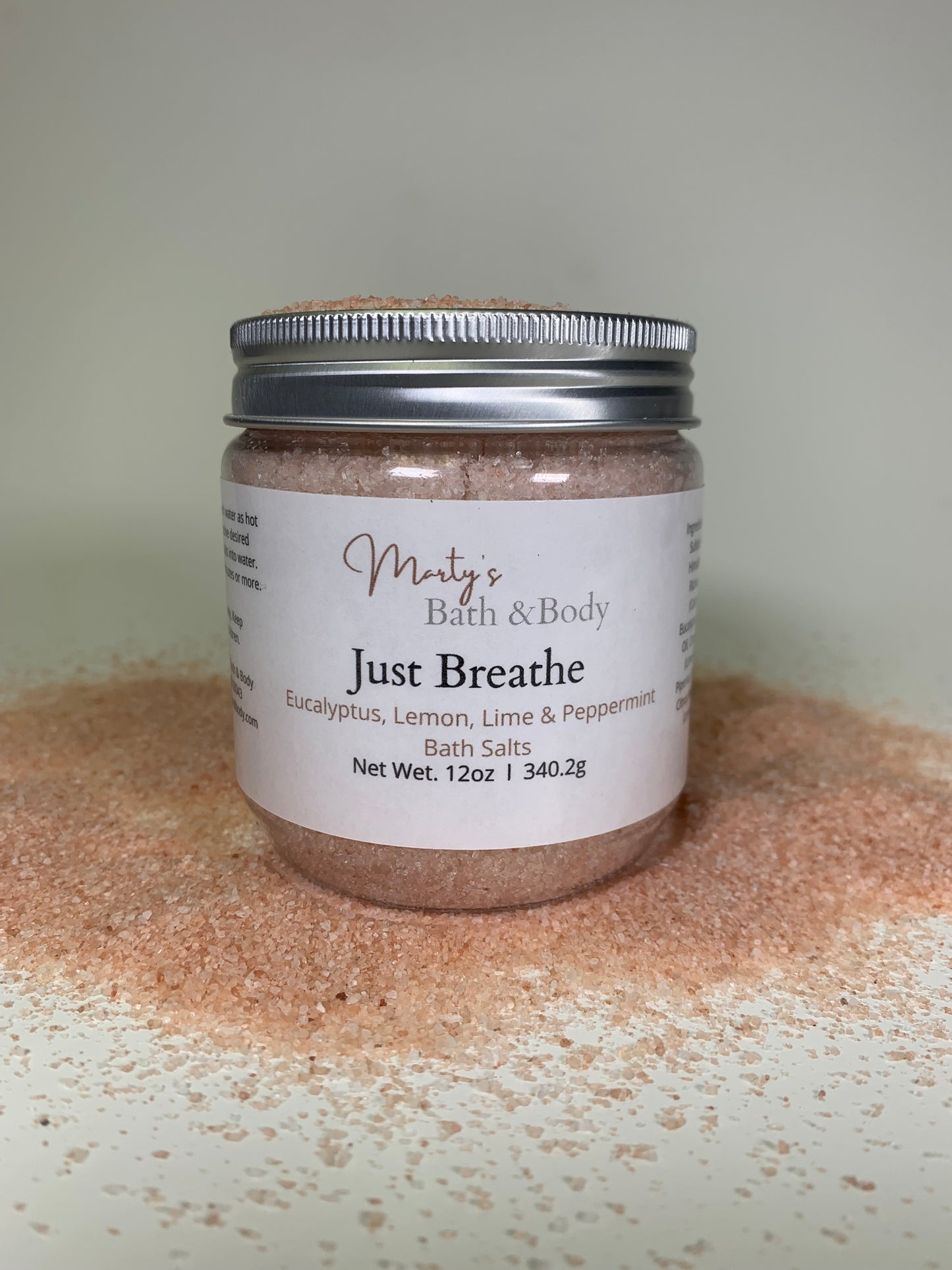 12 oz jar of Just Breathe handmade bath salts/bath soak surrounded by pink Himalayan salt.