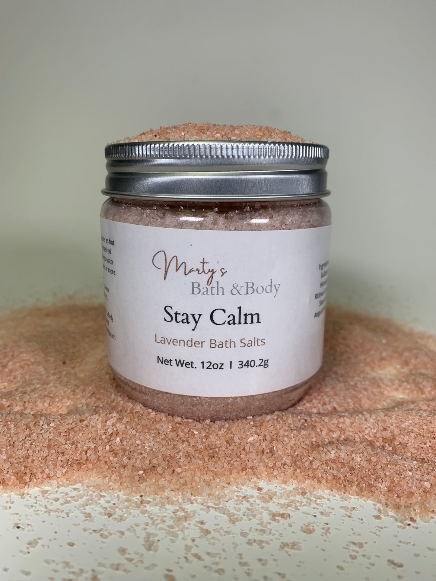 12 oz jar of Stay Calm lavender bath salt/bath salts, surrounded by natural  Himalayan Pink Salt.