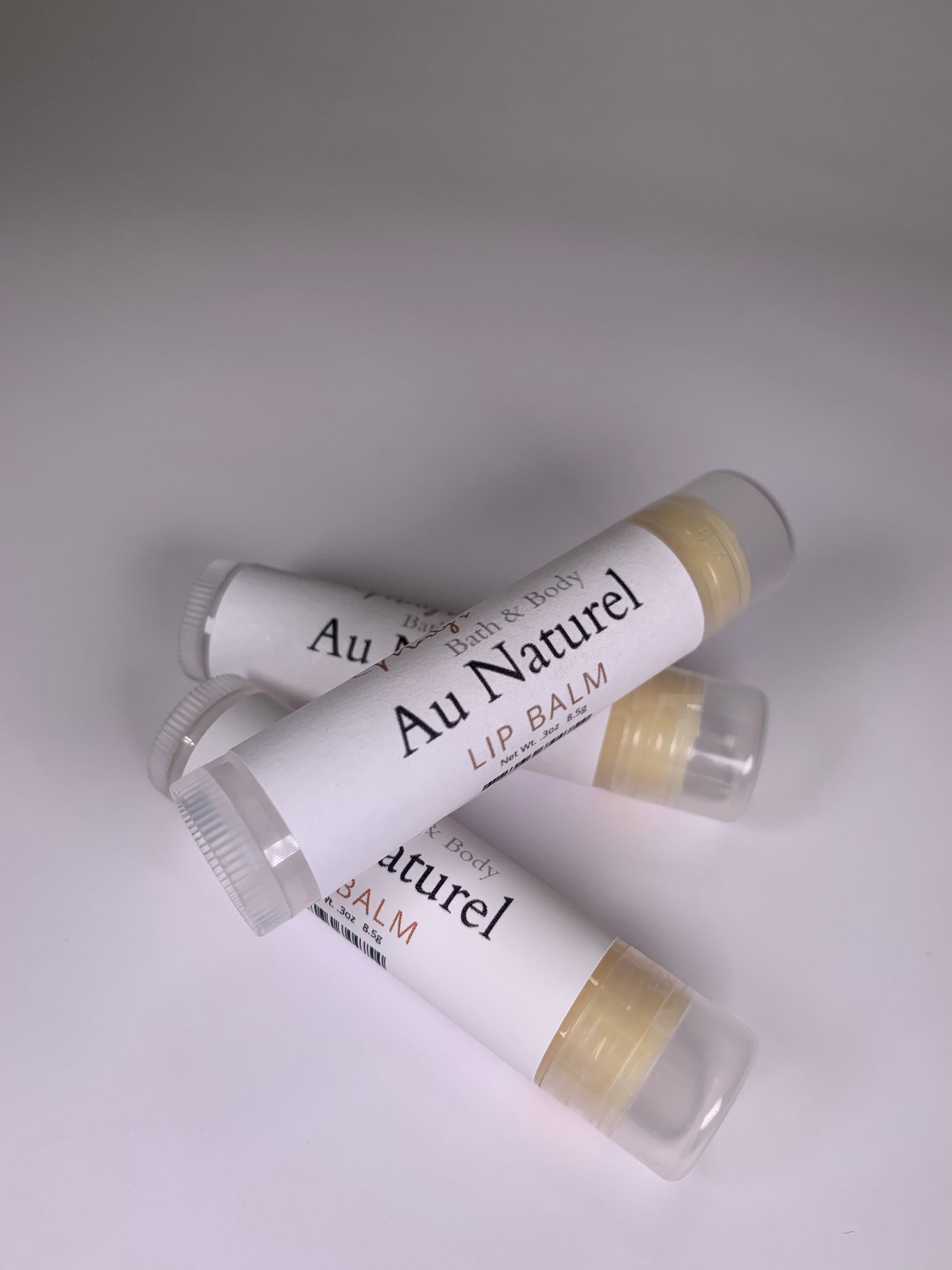 Three Au Naturel flavored lip balms. One laying across the other two. They are handmade of all natural, plant-based ingredients a