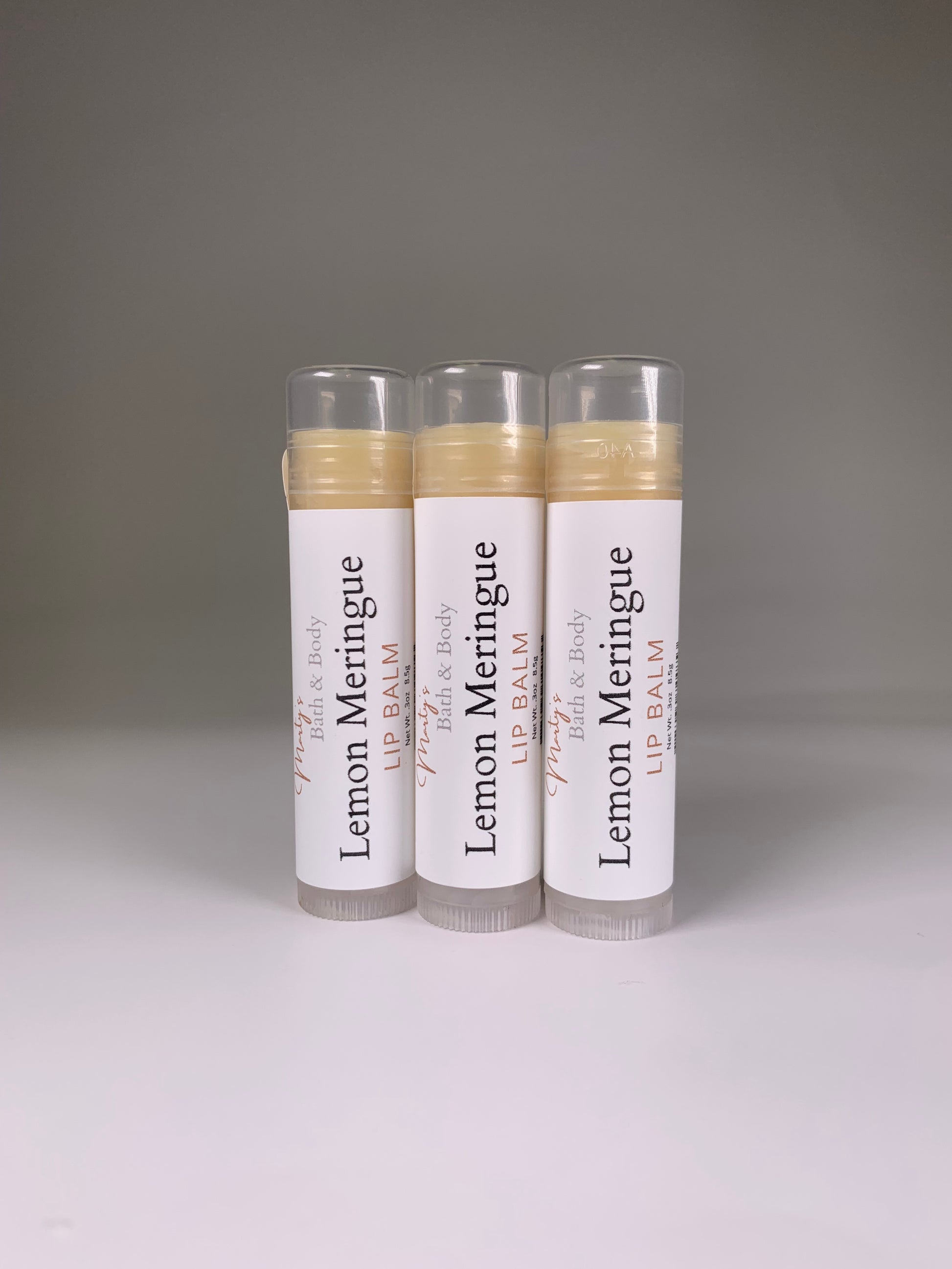 Three plant-based lemon meringue flavored lip balms placed standing up.