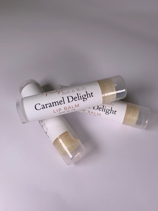 Caramel Delight Lip Balm. Three caramel flavored lip balms with one laying across the other two. Handmade, all natural, plant-based lip balm with no synthetic flavors or colors.