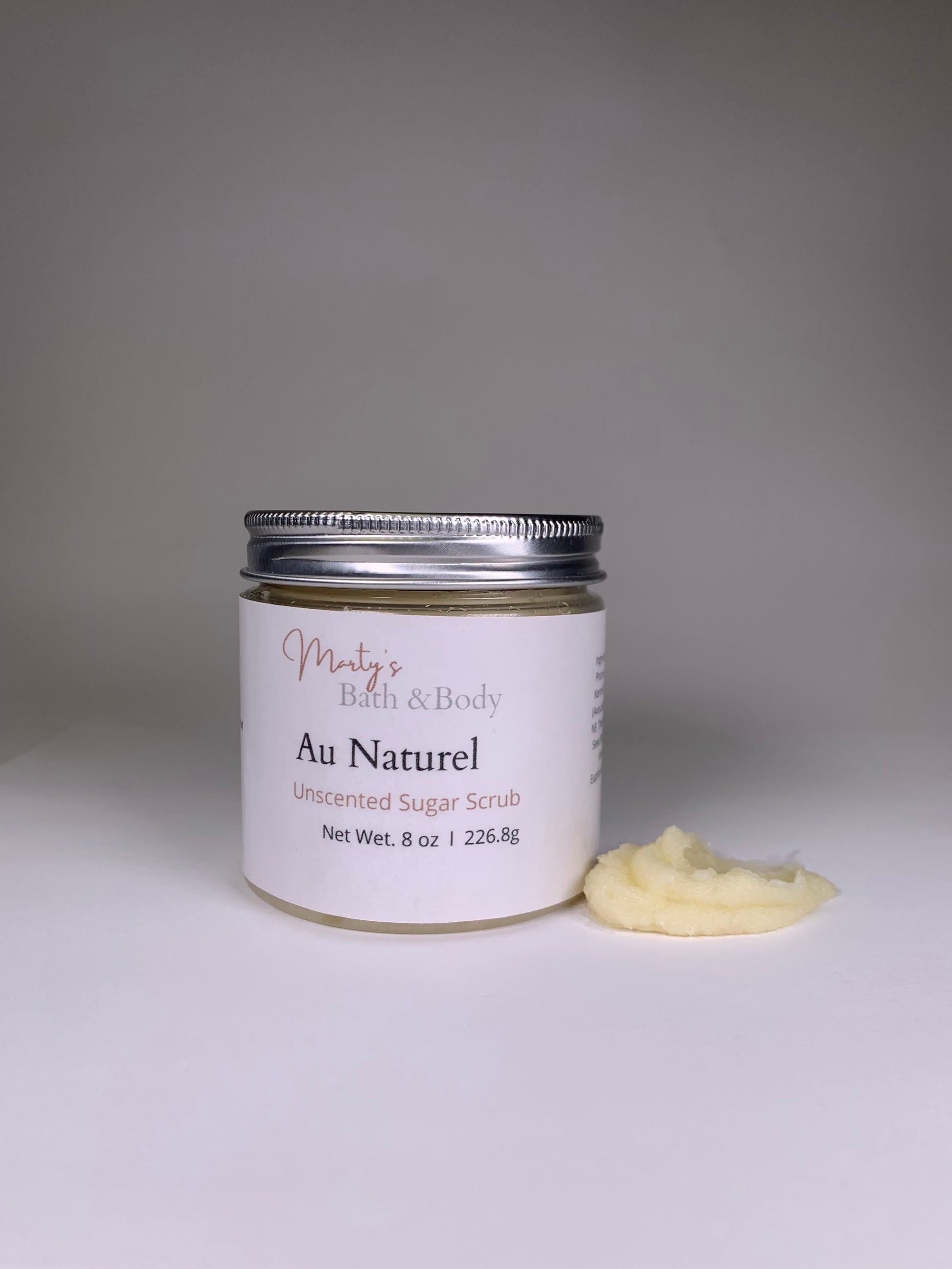 8oz jar of Au Naturel unscented sugar scrub with a small sample of the scrub next to it.